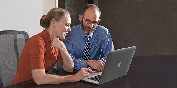 man and woman in an office looking at a laptop